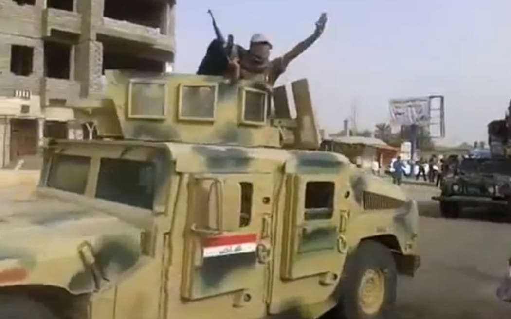 An image taken from a video put on YouTube on Tuesday allegedly showing ISIS militants parading with an Iraqi army vehicle in the northern city of Baiji.