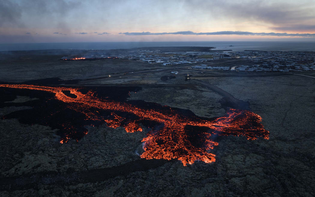 Lava explosions and billowing smoke are seen near residential buildings in the southwestern Icelandic town of Grindavik after a volcanic eruption on January 14, 2024.