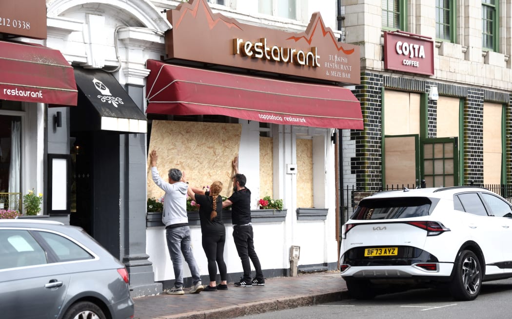 People board up a restaurant ahead of an anti-immigration protest called by far-right activists in Birmingham, central England, on August 7, 2024. Thousands of riot police stood ready Wednesday as Britain remained on alert for disturbances during far-right protests across the country. Nightly riots, during which mosques and migrant targets have been attacked, erupted after three children were murdered in Southport on July 29. (Photo by Darren Staples / AFP)
