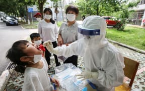 This photo taken on May 16, 2020 shows a medical worker taking a swab sample from a child to be tested for the COVID-19 coronavirus, in a street in Wuhan, in China's central Hubei province.