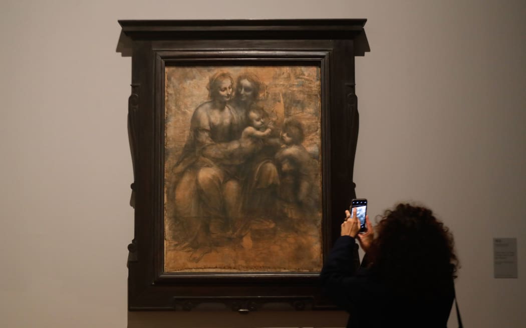 A woman looks at a drawing by Leonardo da Vinci's  " The Virgin, the Child Jesus with Saint Anne and Saint John the Baptis ", during the opening of the exhibition " Leonardo da Vinci ", on October 22, 2019 at the Louvre museum in Paris.