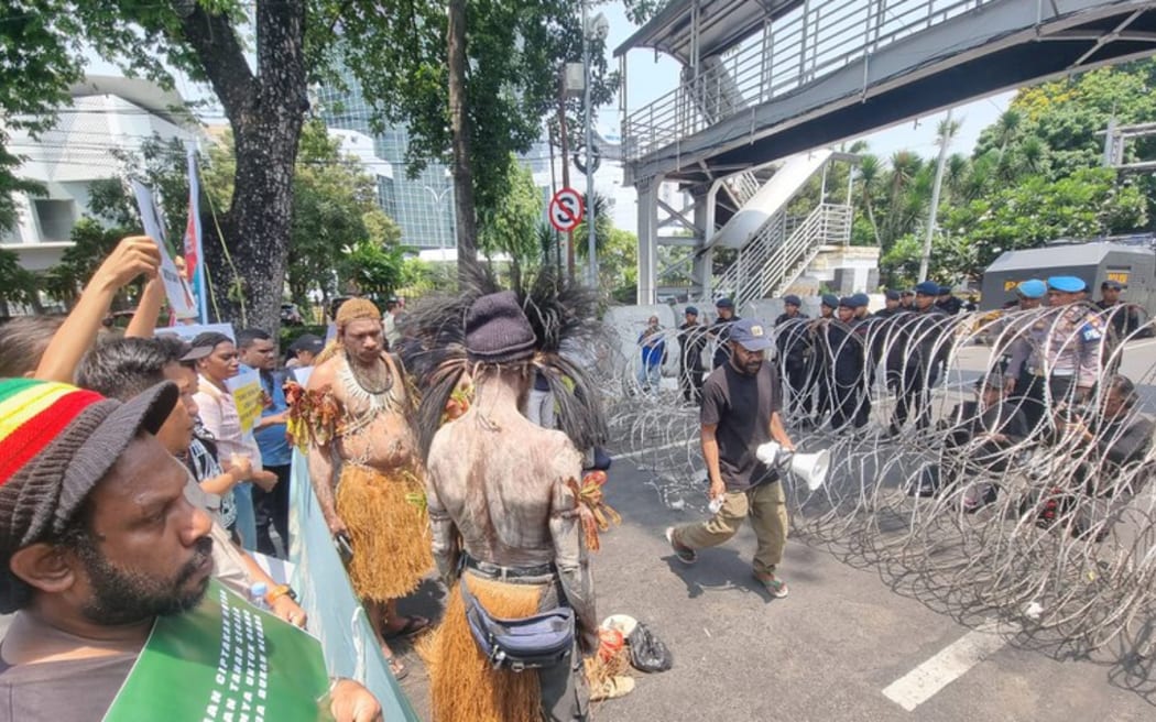 Security personnel watch from behind barbed wire as indigenous Papuans from Merauke in eastern Indonesia protest in Jakarta against plans to convert indigenous and conservation lands into sugar cane plantations and rice fields, 16 October 2024.