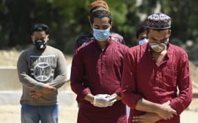 Relatives and friends offer a prayer during the funeral of a Covid-19 coronavirus victim at a graveyard in New Delhi on April 3, 2021. (Photo by Sajjad HUSSAIN / AFP)