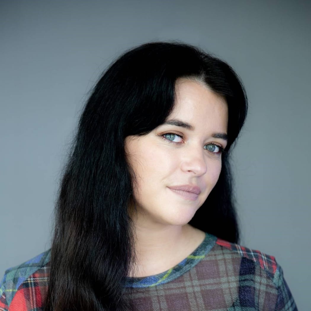 Maggie Tweedie relaxed smile in front of grey background