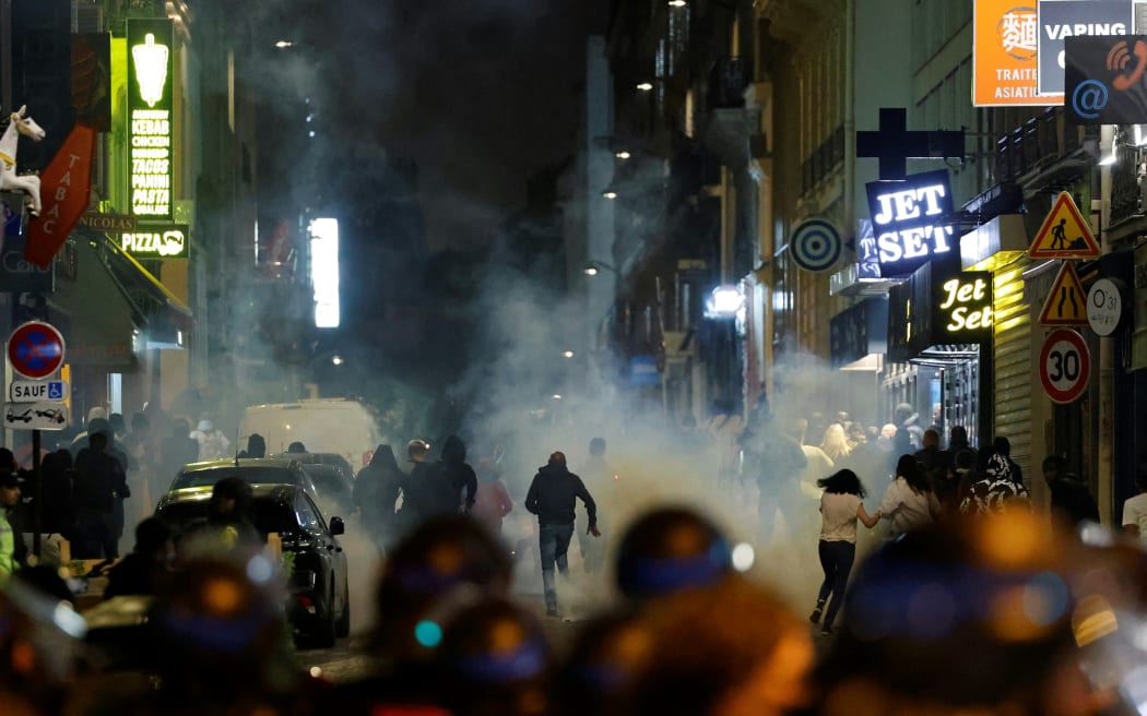 Demonstrators run as French police officers use tear gas in Paris on 2 July, 2023, five days after a 17-year-old man was killed by police in Nanterre, a western suburb of Paris.