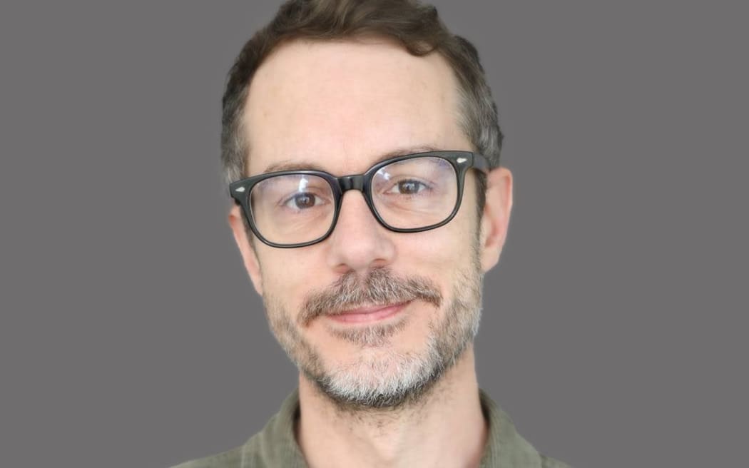 Tony Stamp relaxed smile with grey background