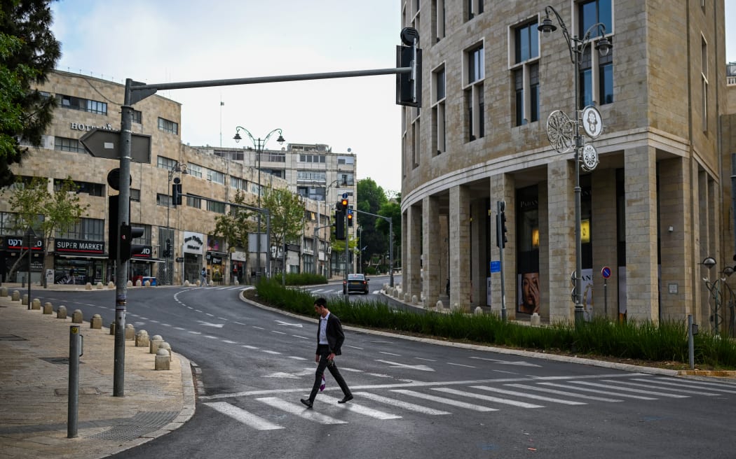 A man crosses an empty street in Jerusalem on April 14, 2024. Iran's unprecedented attack on Israel has been "foiled," the Israeli army announced on April 14, with almost all of the more than 200 missiles and drones intercepted with the help of the United States and allies. (Photo by Ronaldo SCHEMIDT / AFP)