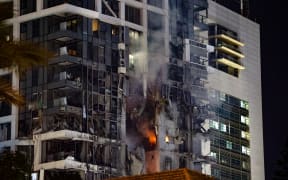 Fire and smoke rise from a building, reportedly hit by a missile fired from Iran, in central Tel Aviv on June 13, 2025. Iran fired a barrage of ballistic missiles at Israel in a counter-strike in the evening on June 13, after an unprecedented onslaught hammered the Islamic republic's top military brass and targeted its nuclear facilities and bases. (Photo by Jack GUEZ / AFP)