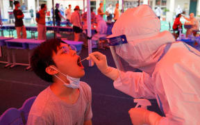 A medical worker takes a swab sample from a citizen at a Covid-19 nucleic acid testing site in Guangling District of Yangzhou, east China's Jiangsu Province, Aug. 11, 2021.