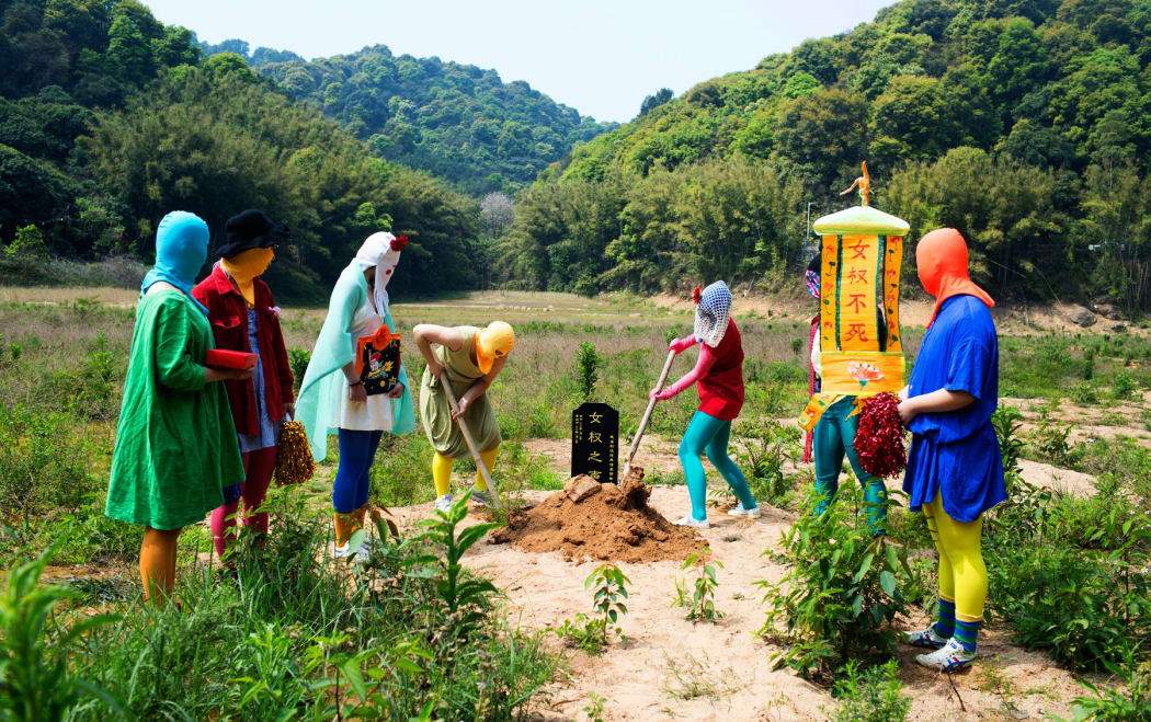 Masked women hold a symbolic funeral for the death of Feminist Voices.