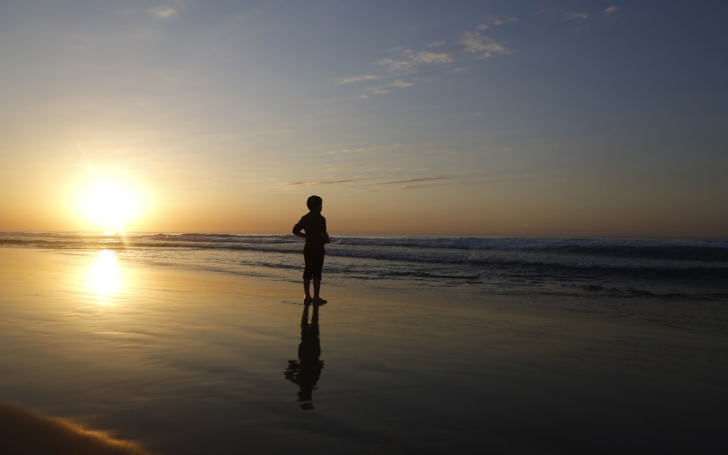 A Palestinian boy stands on the beach during the last sunset of 2014 off the coast of Gaza City.