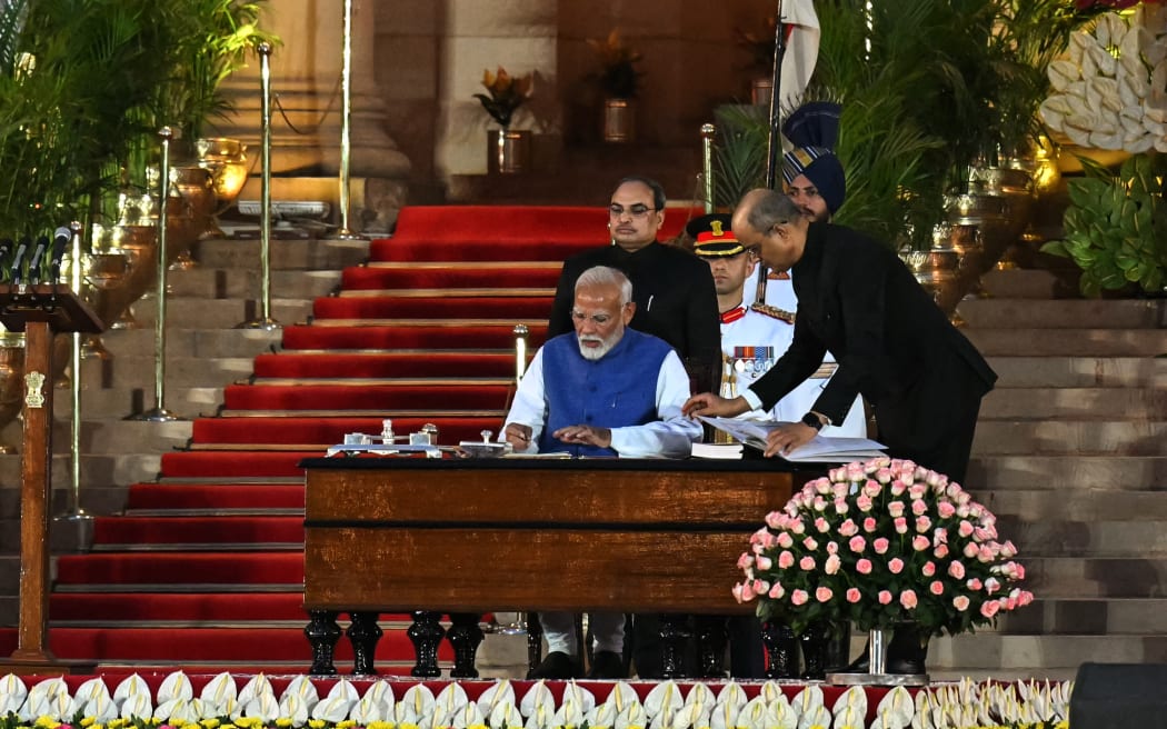 India’s Bharatiya Janata Party (BJP) leader, Narendra Modi (C) signs after taking the oath of office for a third term as the country's Prime Minister during the oath-taking ceremony at presidential palace Rashtrapati Bhavan in New Delhi on June 9, 2024.