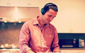 A man holding a tablet computer, wearing bluetooth headphones