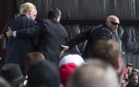 The US Secret Service swarms around Republican Presidential candidate Donald Trump after a bottle was thrown on stage in Ohio.