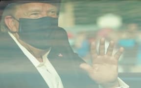 US President Trump waves from the back of a car in a motorcade outside of Walter Reed Medical Center, Maryland.