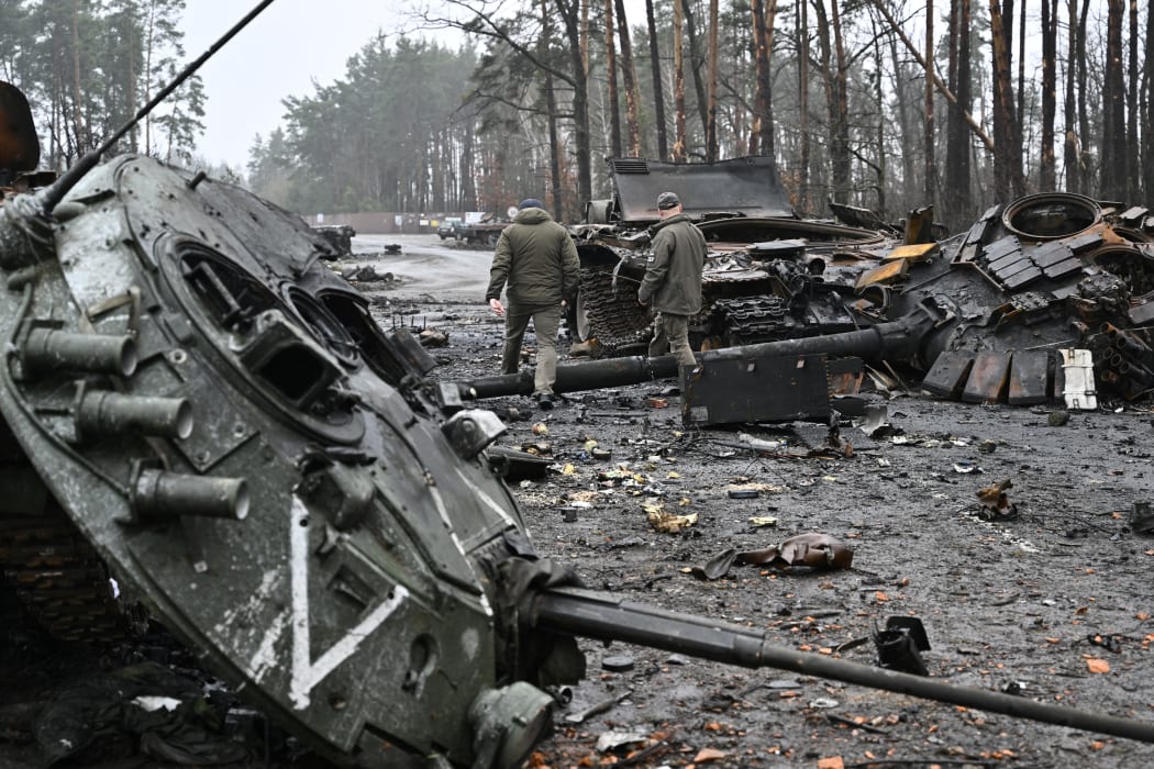 Ukrainian servicemen walk next to destroyed Russian tanks and armored personnel carriers in Dmytrivka village, west of Kyiv, on 2 April, 2022.