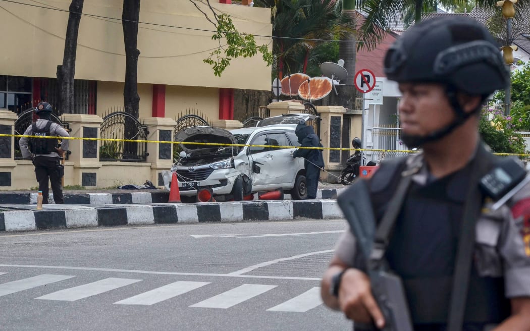 Police stand guard as a car that was used to attack the police headquarters is examined in Pekanbaru on May 16, 2018.