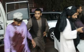Men carry a wounded man onto a stretcher outside a hospital following a car bomb in Lashkar Gah, the capital of Helmand province, on March 23, 2018.