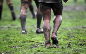 Players walk through the mud.