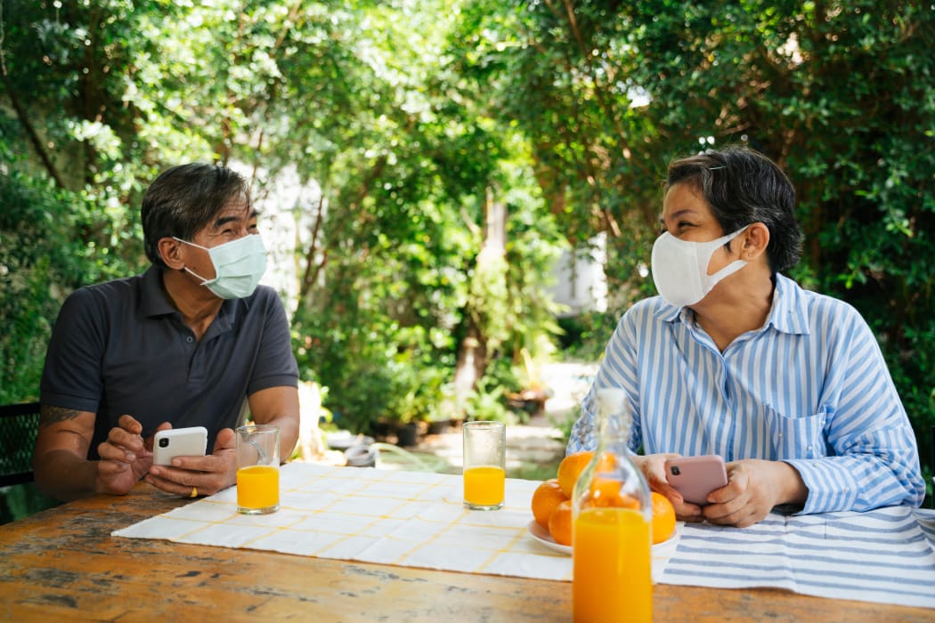 Couple wearing masks picnicking outdoors.