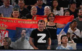 A man wearing a T-shirt with the 'Z' symbol representing support for Russia's invasion of Ukraine' watches the men's singles quarter-final match between Serbia's Novak Djokovic and Russia's Andrey Ruble, next to supporters holding up Serbian flags, at the Australian Open on 25 January.