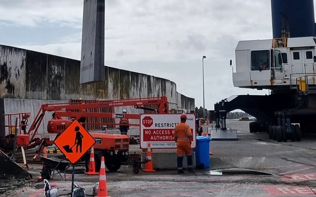 The first of seven, 15-tonne reinforced concrete replacement panels is lifted by a Port Taranaki mobile harbour crane.