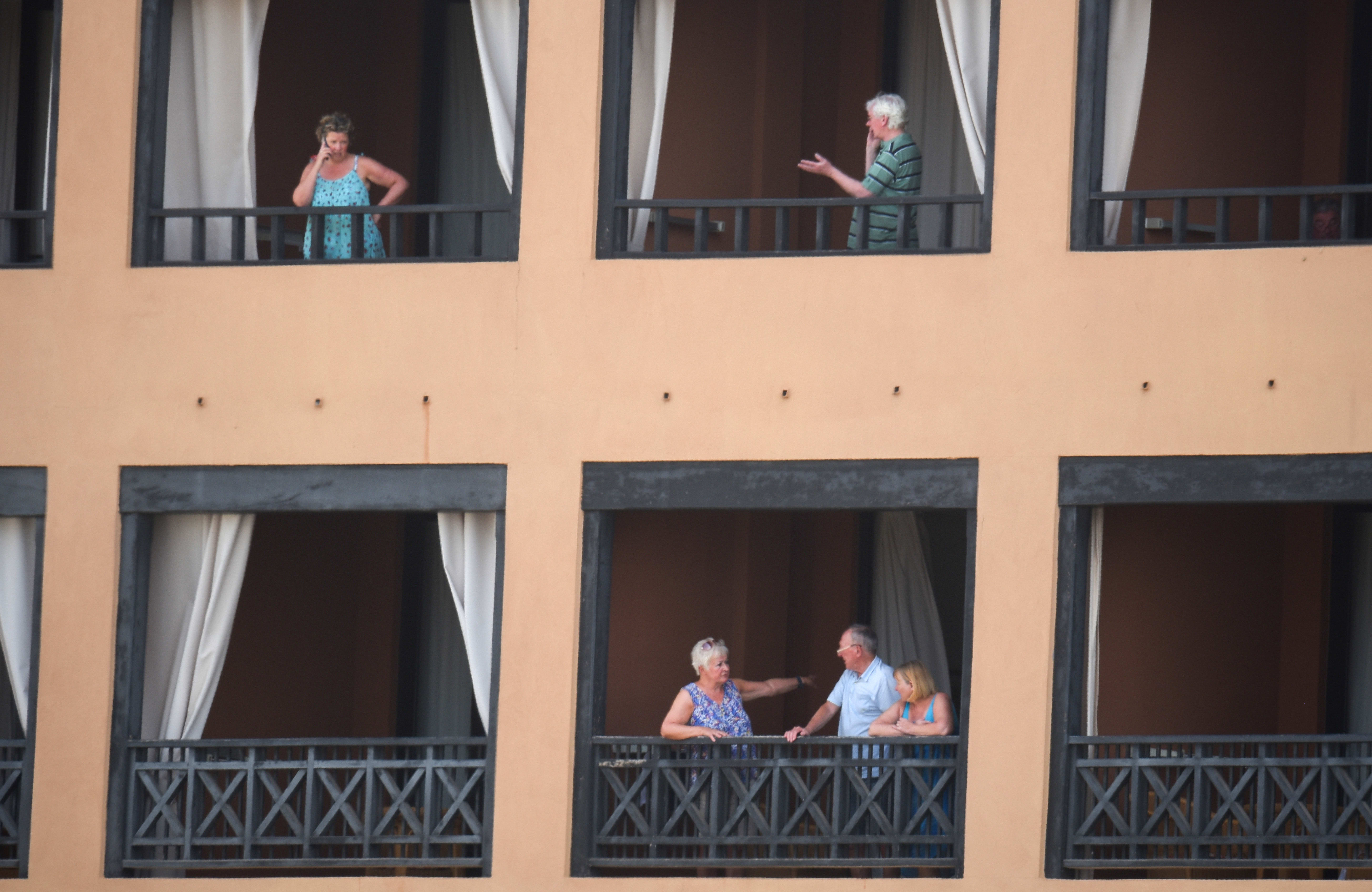 Tourists stand on the balconies of their rooms at a hotel in Tenerife, in Spain's Canary Islands. Hundreds of people were confined to their rooms after an Italian tourist was hospitalised with a suspected case of coronavirus.