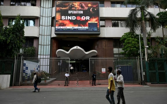Pedestrians walk past a digital broadcast showing the Indian government’s military action code named Operation Sindoor, in Mumbai on May 7, 2025, as border tensions surge. India and Pakistan exchanged heavy artillery along their contested frontier on May 7, after New Delhi launched deadly missile strikes on its arch-rival in the worst violence between the nuclear-armed neighbours in two decades. India conducted several civil defence drills on May 7, while schools in Pakistan's Punjab and Kashmir were closed, local government officials said. (Photo by Indranil Mukherjee / AFP)