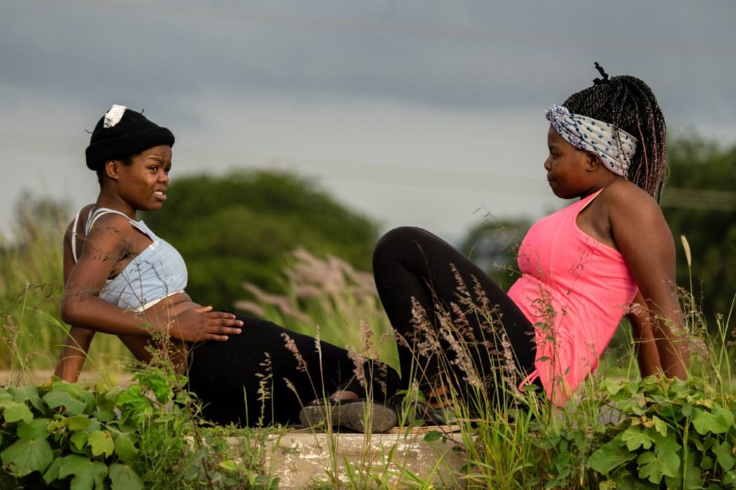 Women sit during a morning workout session on the side of the road on January 27, 2019, near the township of Emakhandeni, outside the Zimbabwean city of Bulawayo