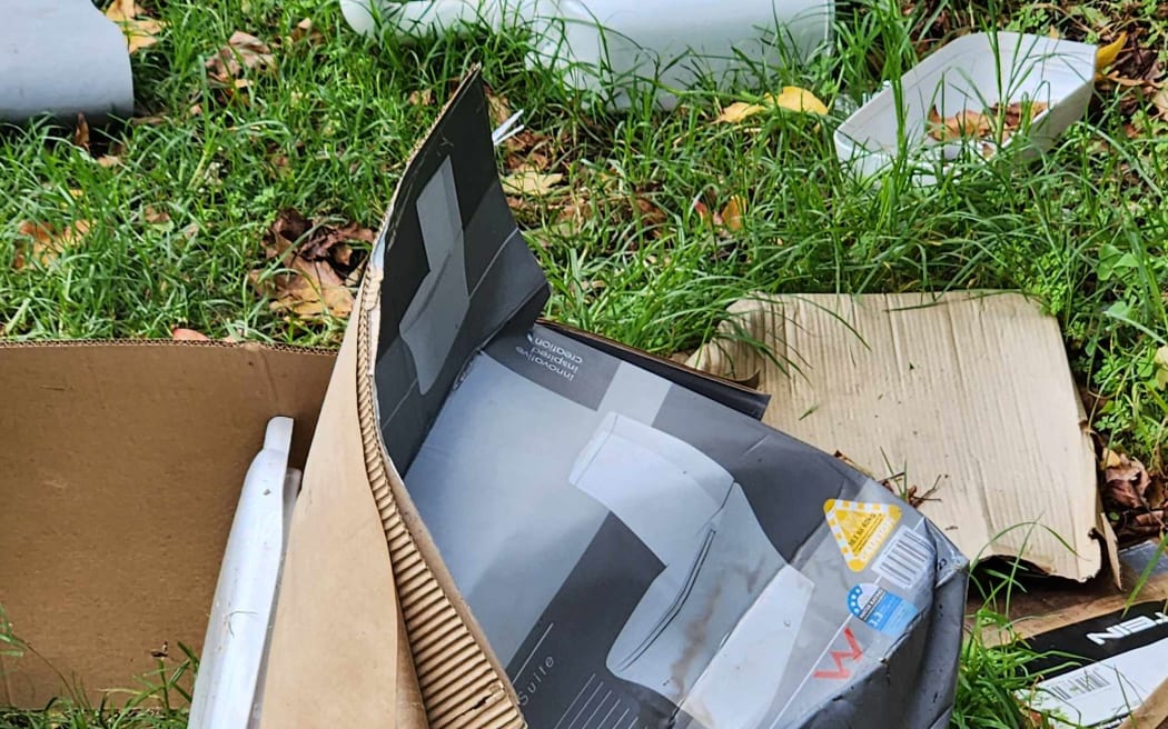 Cardboard and rubbish lying on grass.