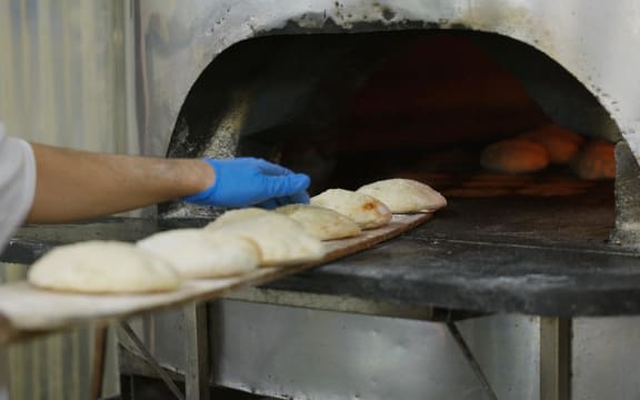 Fresh round bread being pulled out of wood fire oven at Zeki's Bakery.
