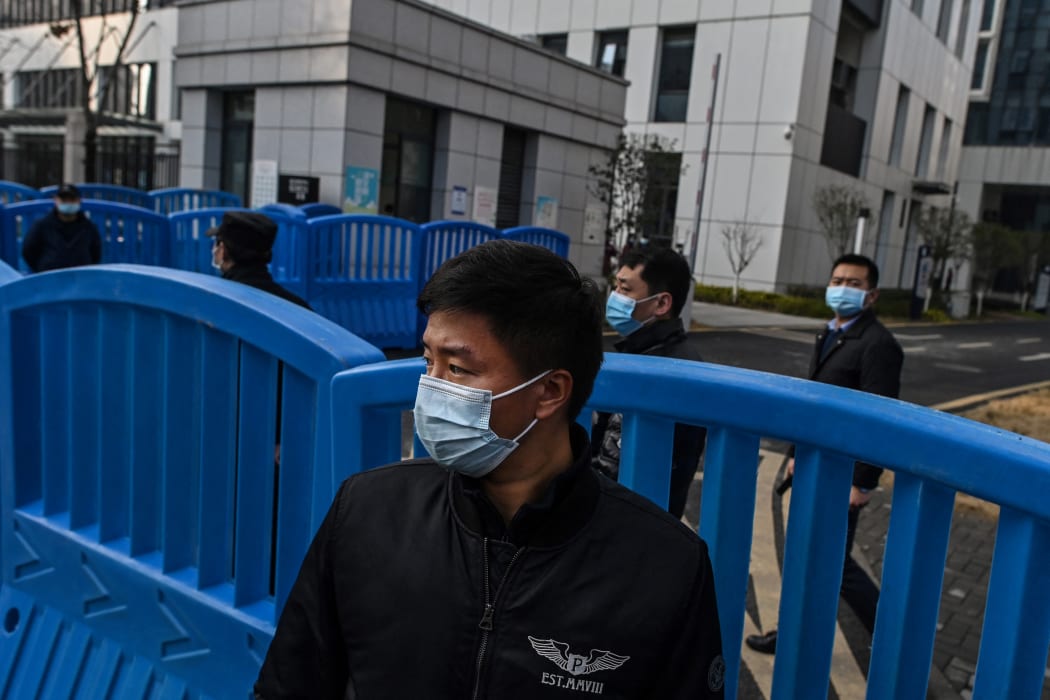 Security guards look on as WHO officers investigate the Wuhan lab.