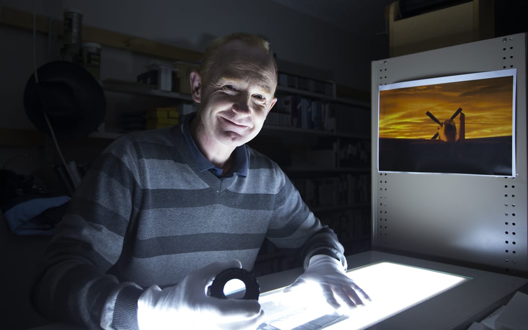 Keeper of Photographs Matthew O'Sullivan using a lightbox to look at a negative in his office.