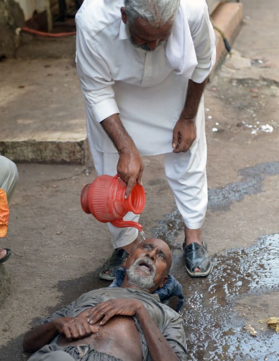 A Pakistani resident helps a heatstroke victim at a market area during a heatwave in Karachi.