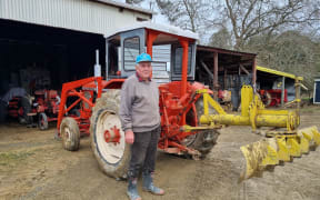 Jim Papps standing in front of one of his tractors following bad weather in Tasman District.