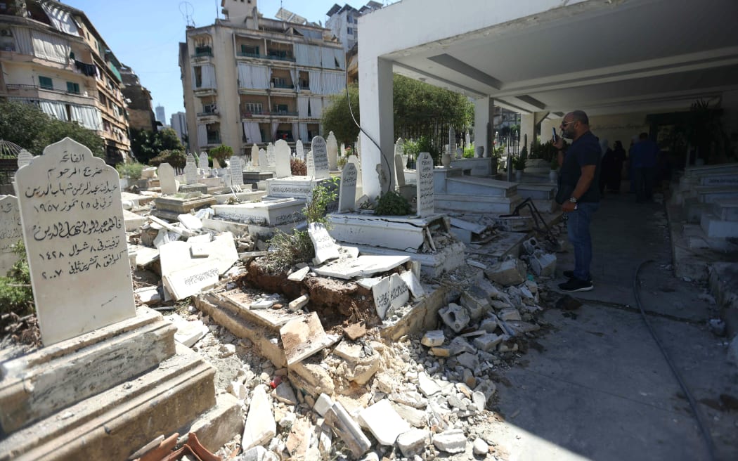 People inspect a cemetery that was damaged an Israeli airstrike targeting a nearby appartment building, on October 3, 2024 in central Beirut. - Five people were killed in an Israeli air raid on a Hezbollah rescue facility in the heart of Beirut late on October 2, according to the Lebanese health ministry. Five people were killed and at least 11 injured in an Israeli raid targeting Bachoura, a district in the centre of the capital, according to a source close to Hezbollah. (Photo by IBRAHIM AMRO / AFP)