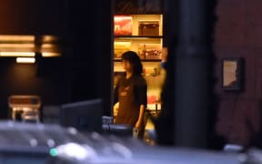 A hostage stands by the front entrance of the cafe as she turns the lights off.