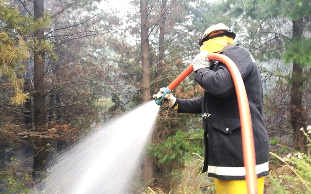 A firefighter dampens a hotspot in the Port Hills.