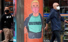 People walk past a poster encouraging vaccinations in Melbourne on September 30, 2021 as the city grapples with a surge in Covid-19 infections recording 1,438 cases, the largest daily total since the start of the pandemic, linked to ongoing street protests and illegal gatherings and house parties