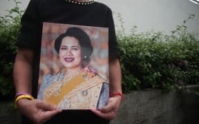 A woman holds photographs of Thailand's Queen Mother Sirikit as people react following the announcement of her death outside King Chulalongkorn Memorial Hospital in Bangkok, Thailand, on October 25, 2025. Queen Sirikit of Thailand passes away. According to the official announcement by the Bureau of the Royal Household, she dies at 21:21 (local time) on Friday, October 24, 2025, at King Chulalongkorn Memorial Hospital in Bangkok at the age of 93. (Photo by Piti Anchaleesahakorn/NurPhoto) (Photo by Piti Anchaleesahakorn / NurPhoto via AFP)