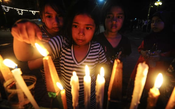 Girls in the southern Thai province of Narathiwat light candles to the late king,  Bhumibol Adulyadej