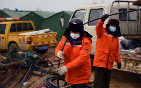 This photo taken on January 20, 2021 shows members of a rescue team working at the site of a gold mine explosion where 22 miners are trapped underground in Qixia, in eastern China's Shandong province.