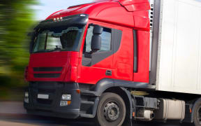 A truck with a red cab picks up speed.