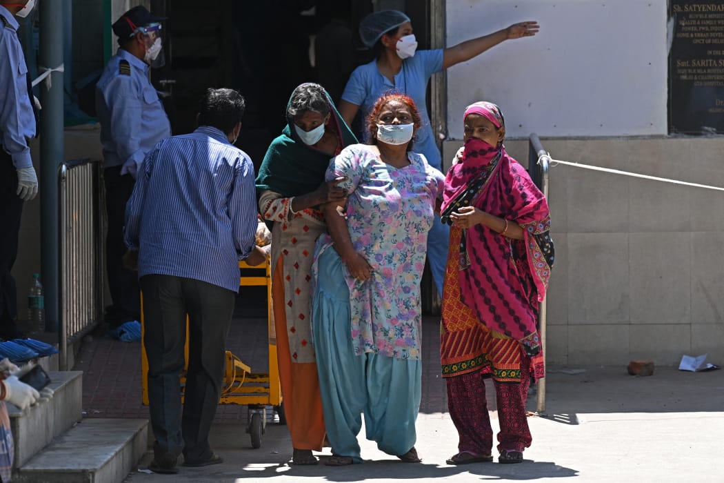 A Covid-19 coronavirus patient is helped by her relatives as she leaves a hospital in New Delhi on April 24.