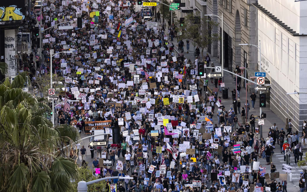 Protesters hold signs as they march during the nationwide "Hands Off!" protest against Trump and his advisor, Tesla CEO Elon Musk, in downtown Los Angeles on April 5, 2025. Protesters flooded the streets of several major US cities on Saturday to oppose the divisive policies of President Donald Trump, in the largest demonstrations since his return to the White House. Opponents of the Republican president's policies -- from government staffing cuts to trade tariffs and eroding civil liberties -- rallied in Washington, New York, Houston, Los Angeles and Florida, among other locations. (Photo by ETIENNE LAURENT / AFP)