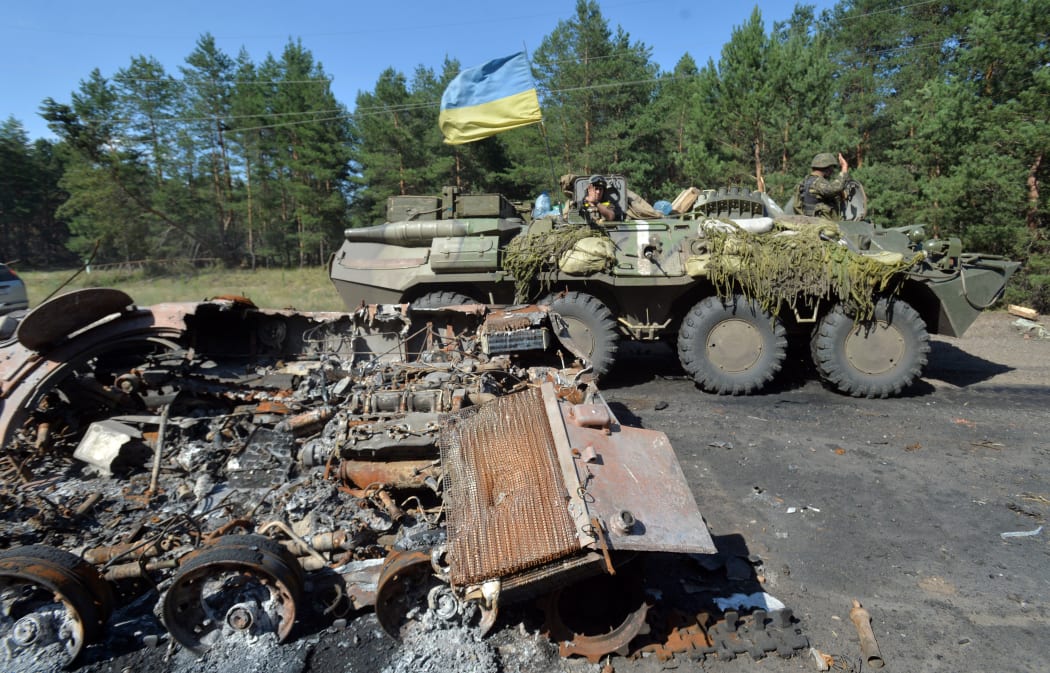 A Ukrainian  armoured personnel carrier drives past a burned armoured vehicle which was used by  pro-Russian militants near Sloviansk.