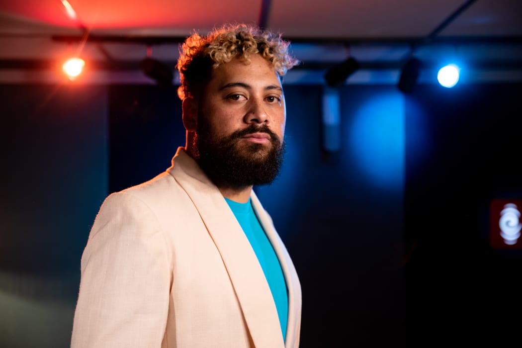 Noah Slee standing in the foreground wearing a white sports coat and azure shirt