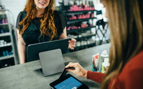 A woman pays for items at a shop counter.