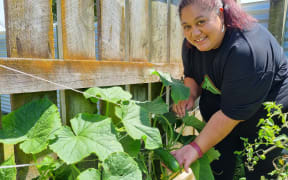 Te Rina Waiwiri shows a cucumber growing in her garden.