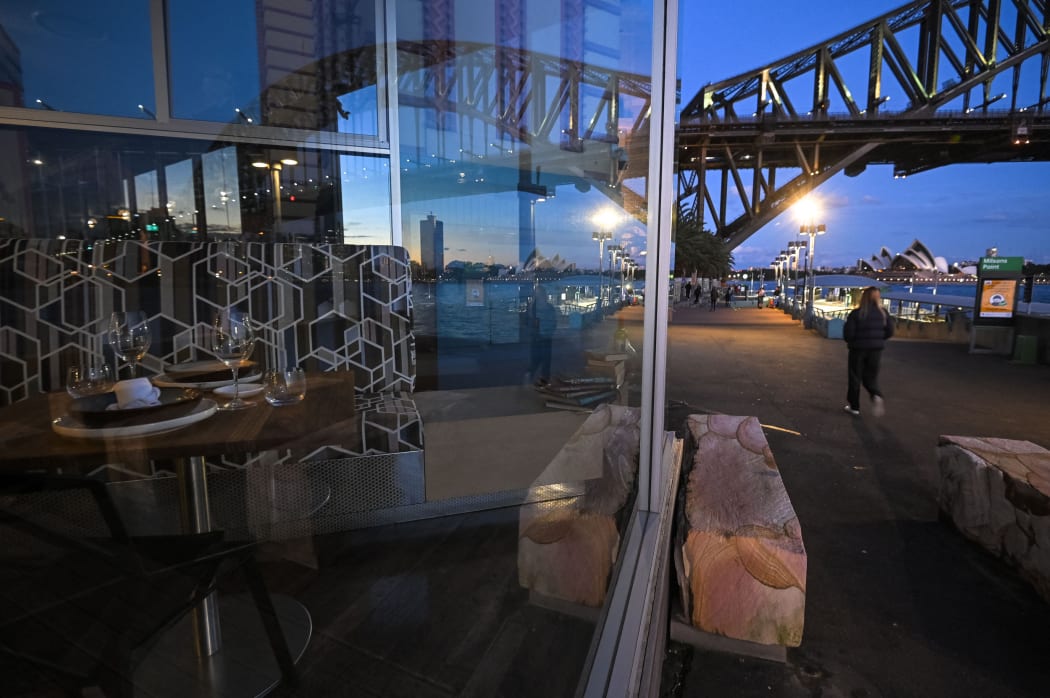 The Sydney Opera House and the Sydney Harbour Bridge are reflected in the window of a closed restaurant at Milson's Point, during lockdown in Sydney